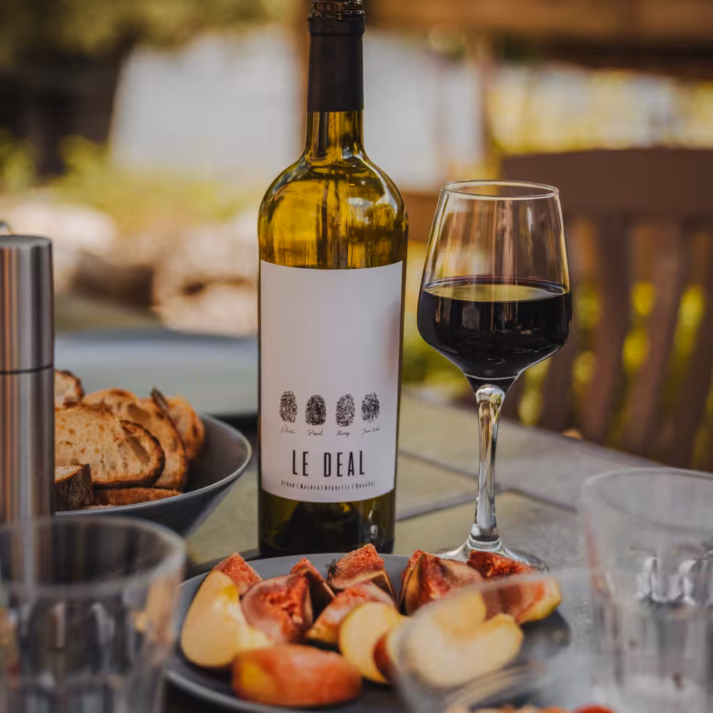 Flasche Wein mit einem gefüllten Weinglas und einem Teller mit Apfelstücken in der Normandie