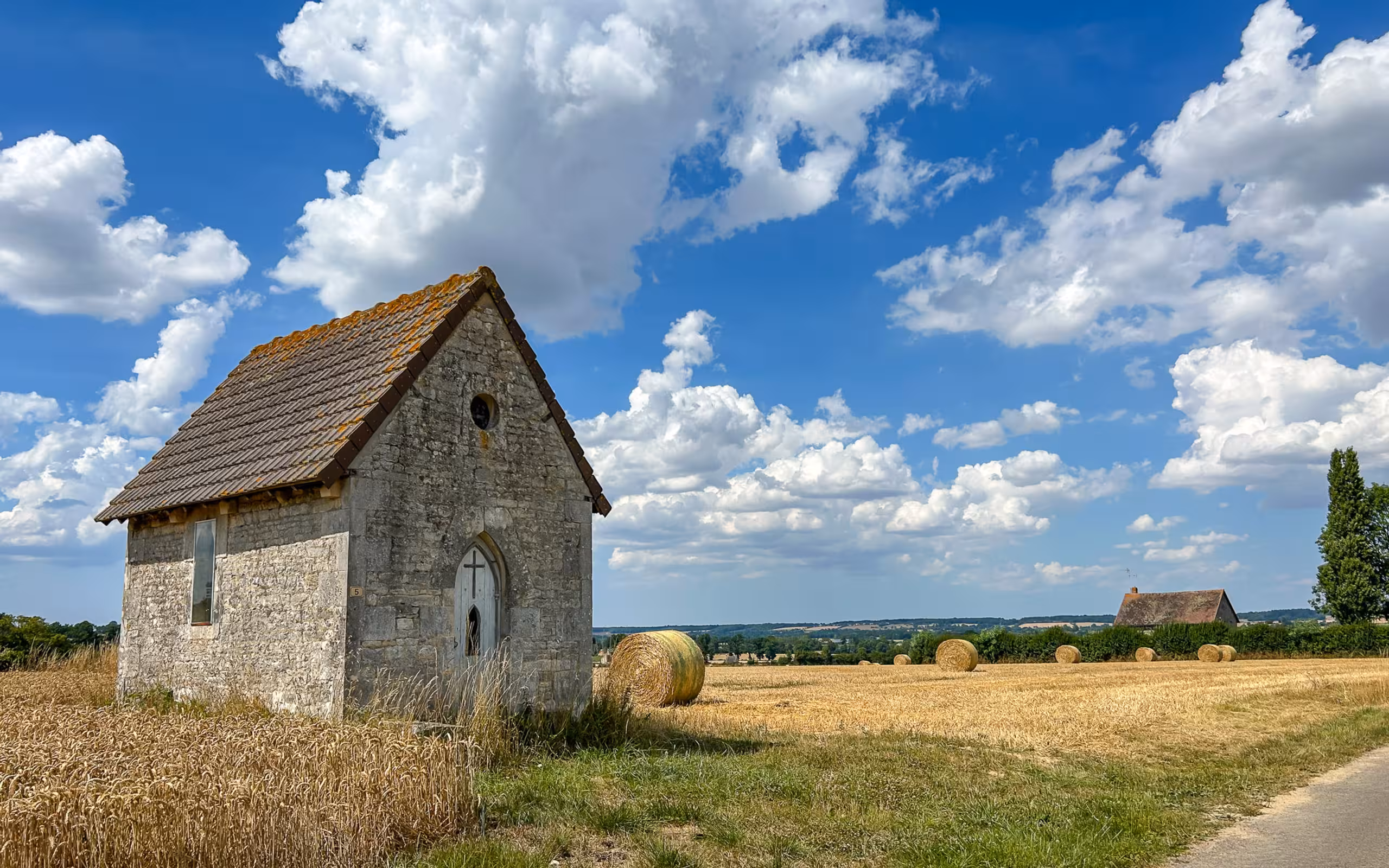 Ein kleines Haus mit einem Feld und Heuballen