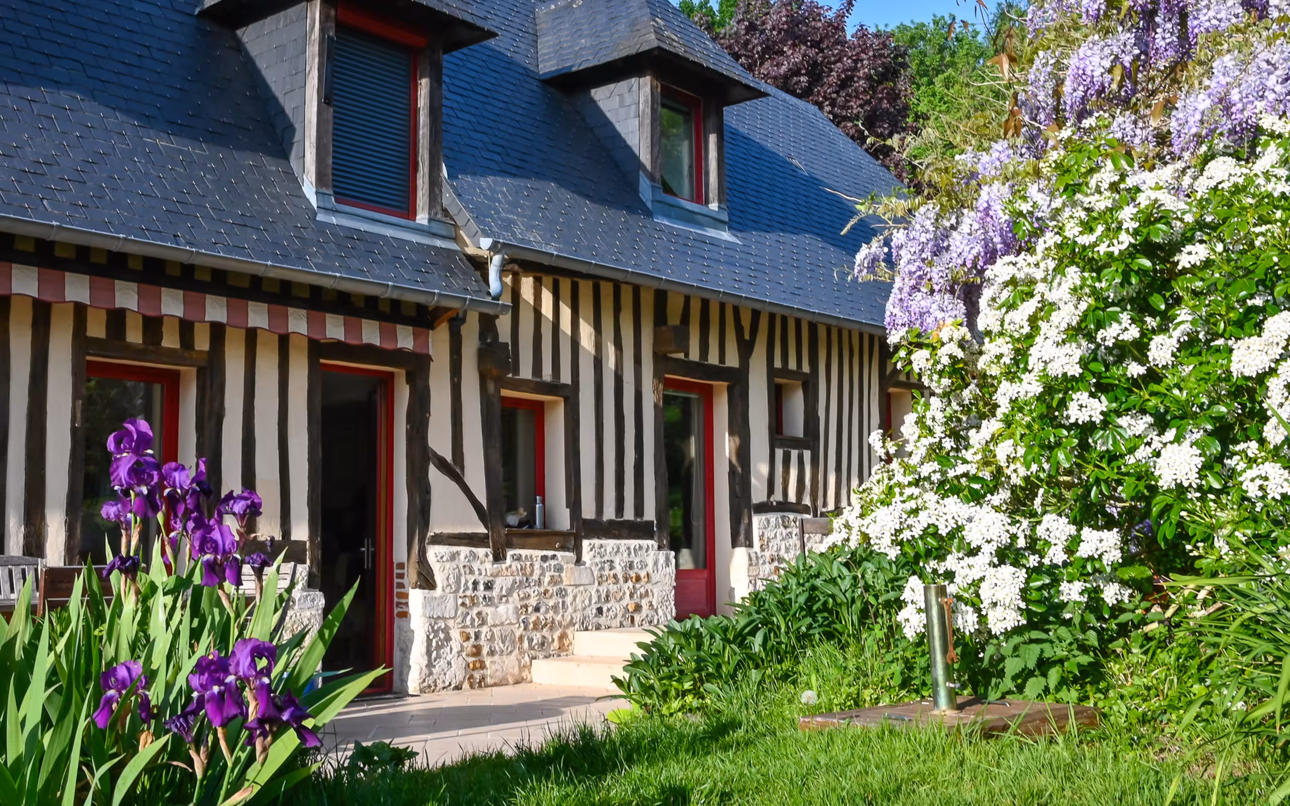 Ein uriges Fachwerkhaus umrahmt von Blumen in der Normandie