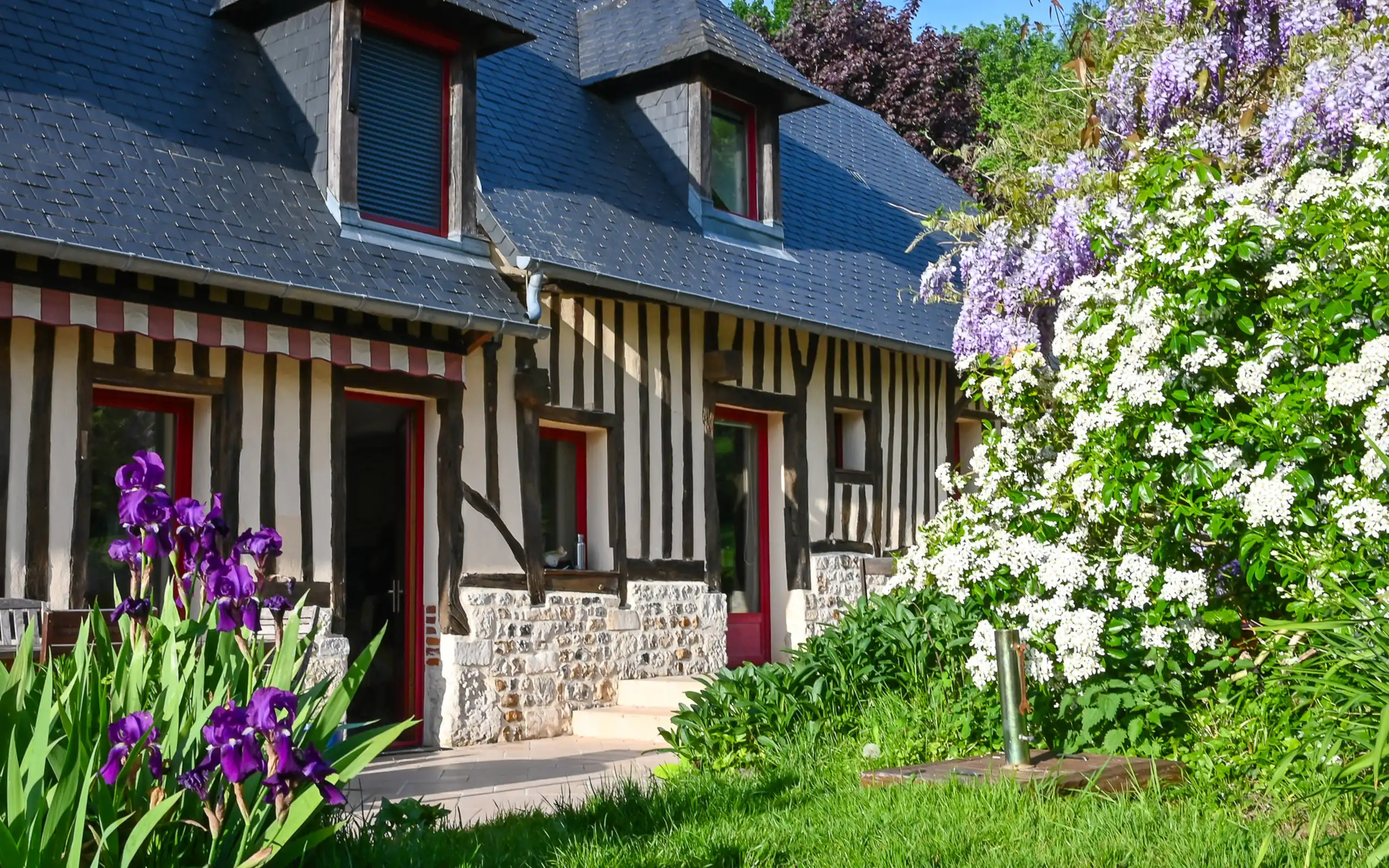 Ein uriges Fachwerkhaus umrahmt von Blumen in der Normandie