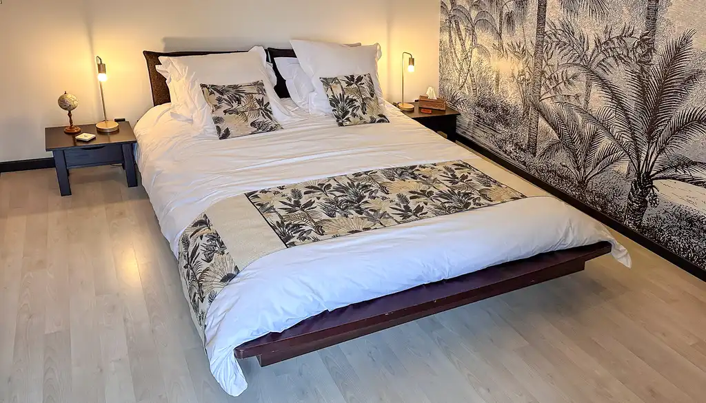 Schlafzimmer mit Bett und floraler Tapete in der Noramndie