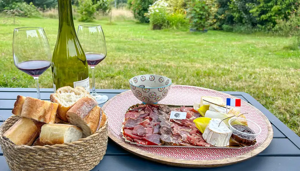 Brot, Wurst, Käse und Wein auf einem Tisch im Garten in der Normandie