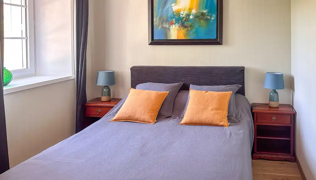 Gemütliches Zimmer mit einem Bett, zwei Nachttischen und einem großem Fenster in der Normandie