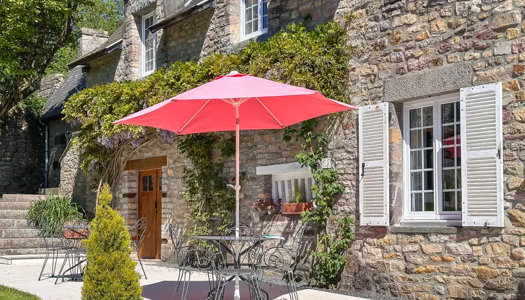 Große Terrasse vor dem Landhaus in der Normandie mit einem roten Sonnenschirm